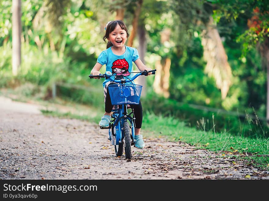 Happy child girl cycling in the park in the village for evening with sunset light exercise