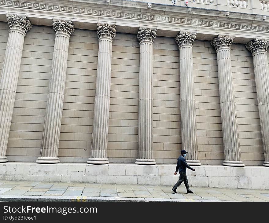 Generic architecture pillars in London and a man walking on the street