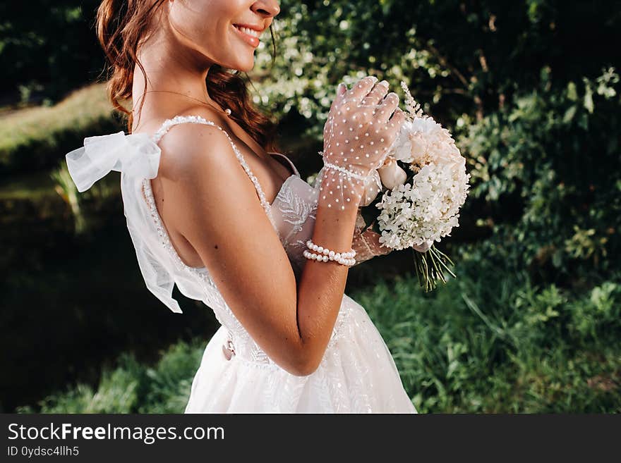 Portrait of an elegant bride in a white dress with a bouquet in nature in a nature Park.Model in a wedding dress and gloves and