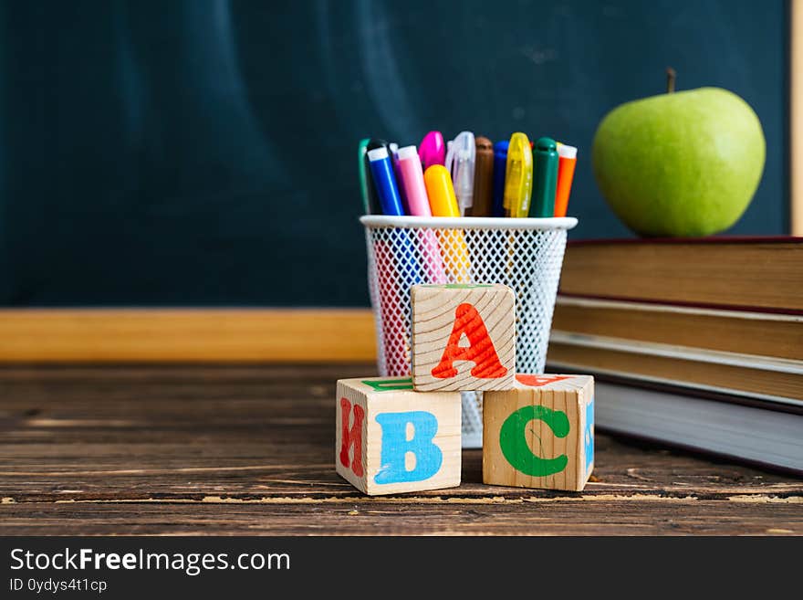 Books And Cubes With The Letters ABC On Wooden Table Against The Background Of The Chalkboard. Back To School