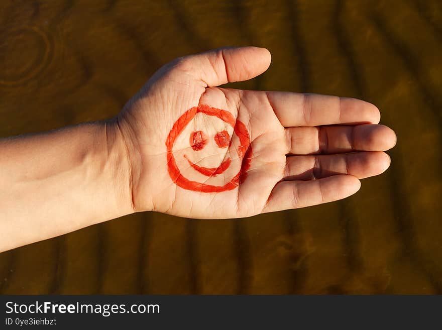 Male Palm With Paint Red Face And Smile On Beach Background