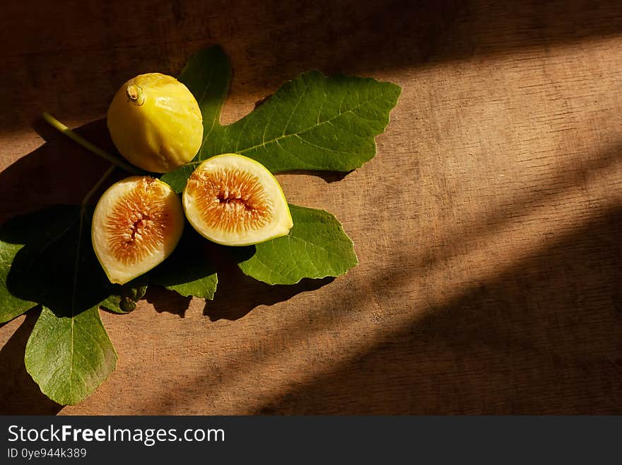 Ripe yellow fig fruit with leaf on wooden background. Harvest and healthy eating concept. Selective focus. Top view.