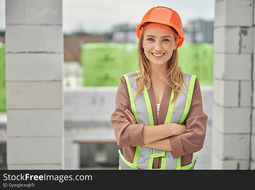 Front view of a young blonde female worker with folded arms posing for the camera. Front view of a young blonde female worker with folded arms posing for the camera