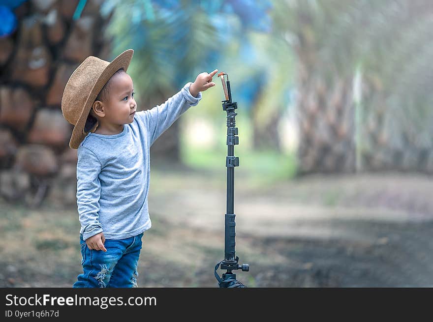 Little asian girl standing and pointing fingers on  digital tablet outdoors in a park. Child interested and eager to learn new