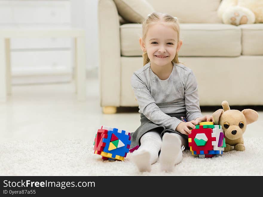 Little Girl Is Playing With Toys While Laying On Floor.