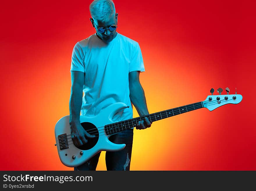 Trendy Hipster Man Play White Bass Guitar In Neon Lights. Rock Music Concept.