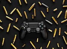 Modern Black Gamepad On A Black Background Among The Spent Cartridges. Game Concept. Shooter Game Royalty Free Stock Images