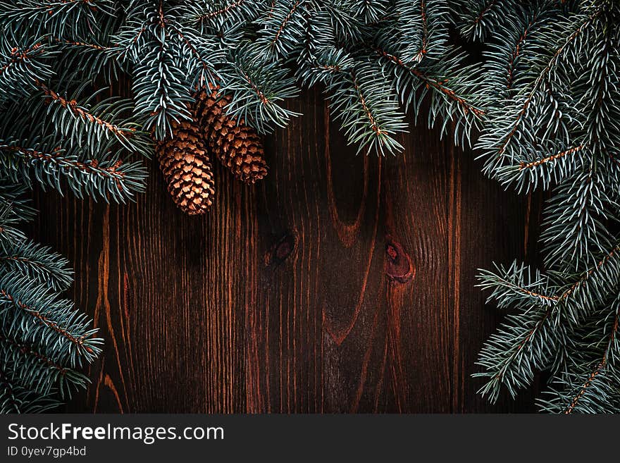 Christmas green frame from fir branches on a vintage brown board background. Frame of fir branches. Christmas card blank