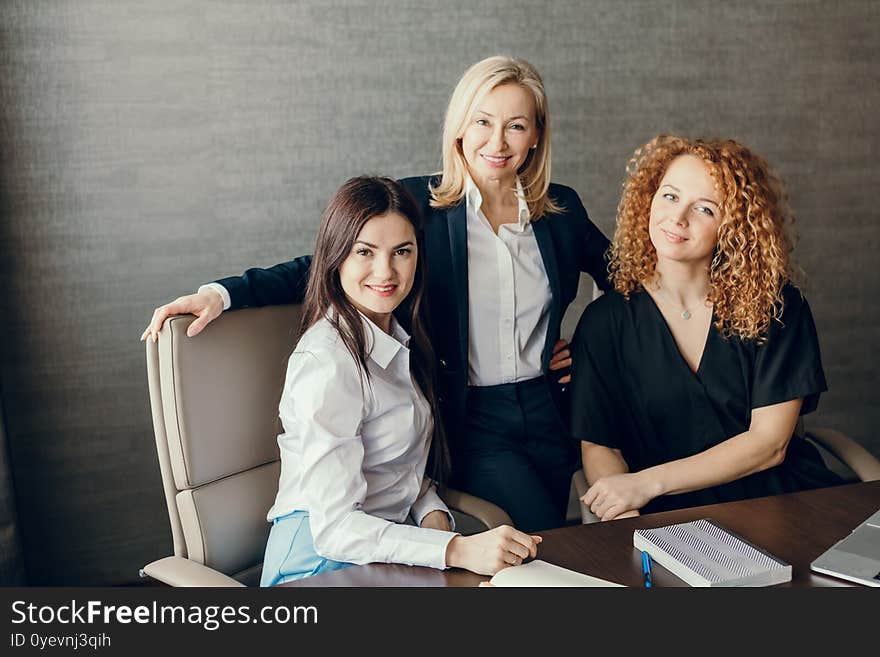 Portrait of blonde female Chief Executive standing in formal suit and two attractive employees from her department. Office portrait of female business professionals. Portrait of blonde female Chief Executive standing in formal suit and two attractive employees from her department. Office portrait of female business professionals.