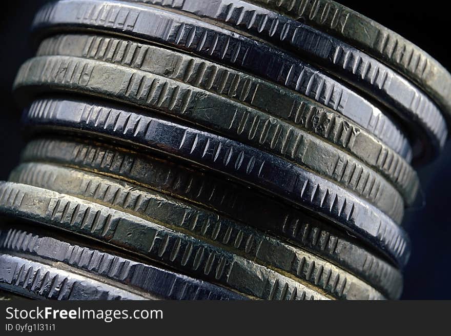 A stack of coins falls on a dark background. Macro