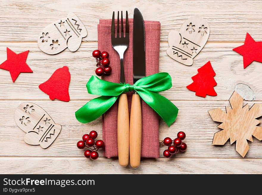 Top view of fork and knife on napkin on wooden background. Different christmas decorations and toys. Close up of New Year dinner concept.