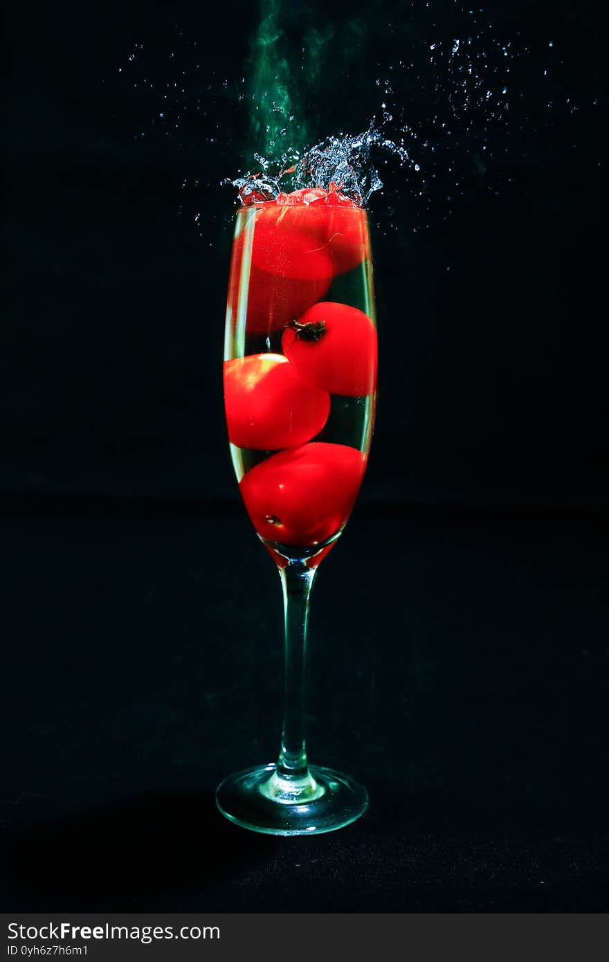 Pictured strawberry shaped grape tomatoes in glass with splash.