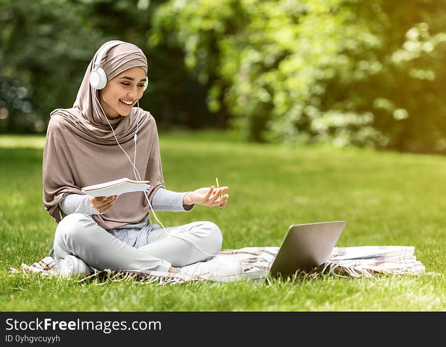 Arab girl studying online at park, using laptop