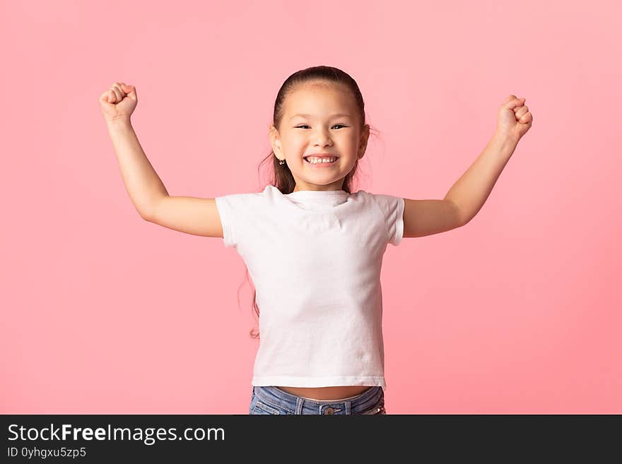 Victory Concept. Overjoyed chinese girl with raised hands making winner gesture, pink background. Victory Concept. Overjoyed chinese girl with raised hands making winner gesture, pink background