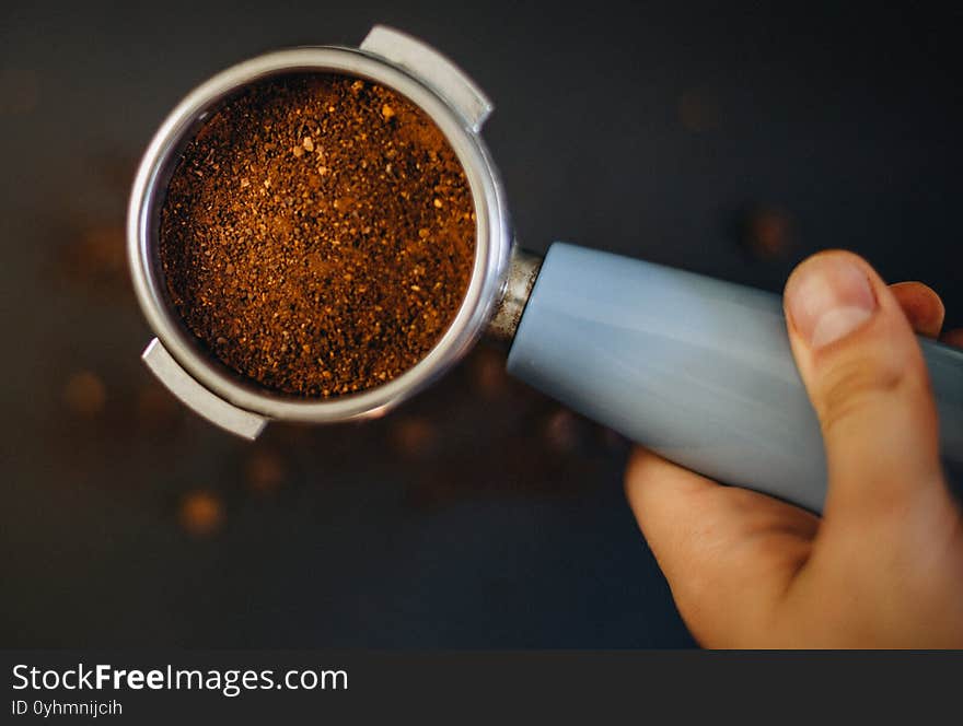 Coffee filter holder with and roasted beans scattered around on a black background in hand. Coffee filter holder with and roasted beans scattered around on a black background in hand