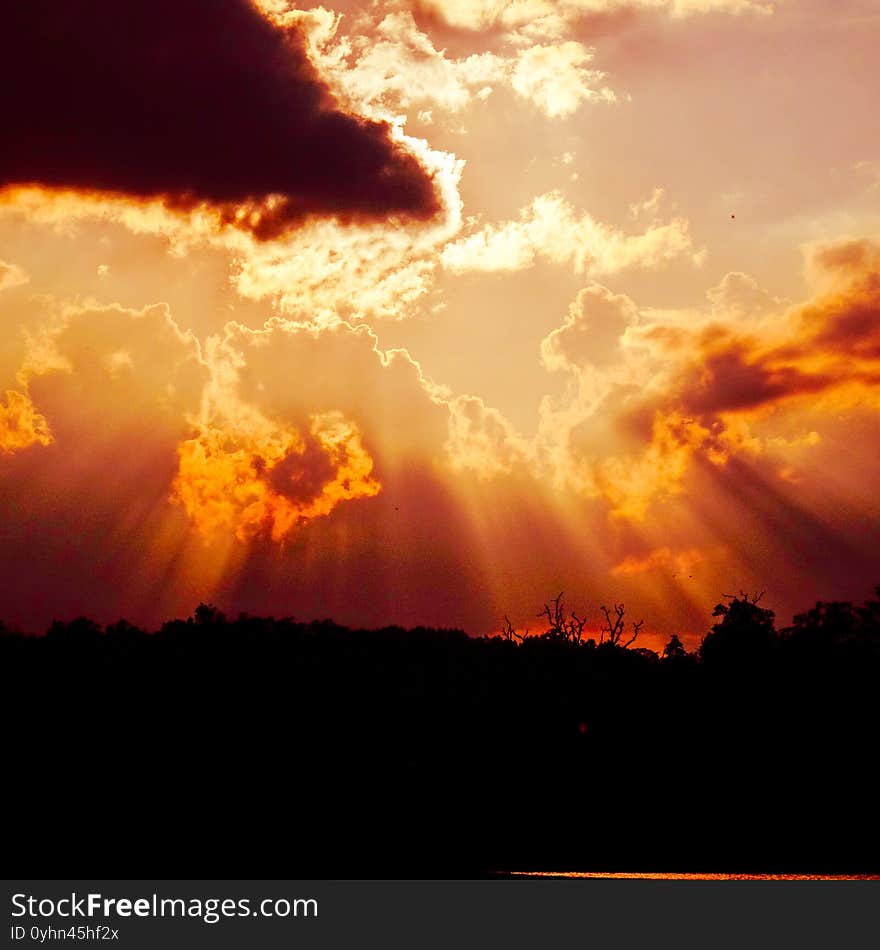 Sun rays pour down in crimson beams from behind a dark cloud to the silhouetted earth below. Michigan/USA. Sun rays pour down in crimson beams from behind a dark cloud to the silhouetted earth below. Michigan/USA.