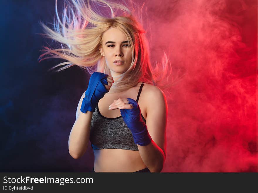 Blonde Female Athlete Is Exercising In Defense On Dark Smoky Background.