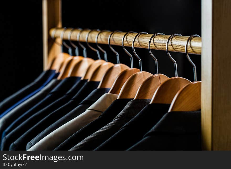 Mens shirts, suit hanging on rack. Hangers with jackets on them in boutique. Suits for men hanging on the rack. Mens suits in different colors hanging on hanger in a retail clothes store, close-up.