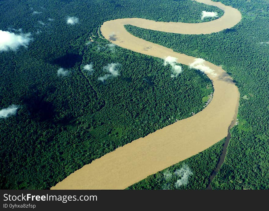 The Amazon, whose water is shaken by rain and colored brown, winds its way through dense green jungles. 
On the shore you can see a few tiny cottages, like dots. View from above from the air from the Amazon. The Amazon, whose water is shaken by rain and colored brown, winds its way through dense green jungles. 
On the shore you can see a few tiny cottages, like dots. View from above from the air from the Amazon.