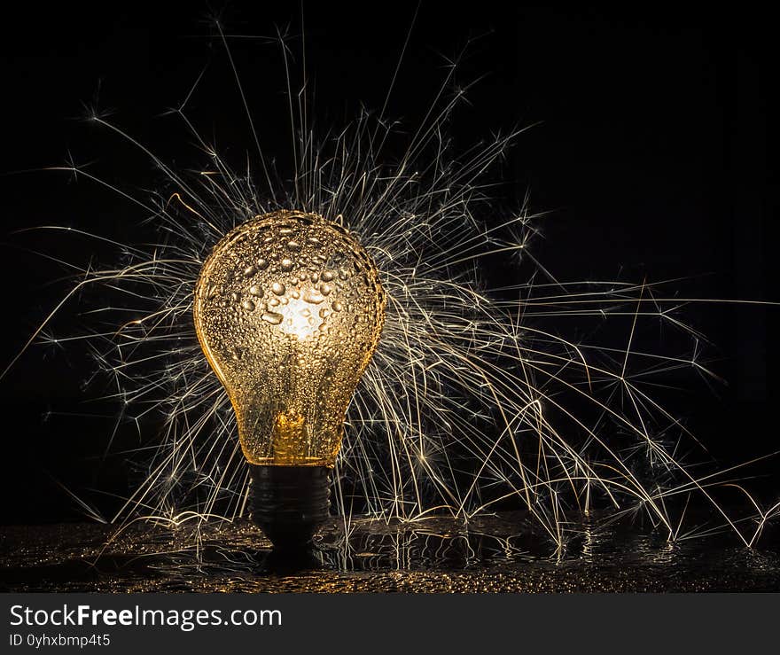 Light Bulb, sparks and the darkness, water drops black background