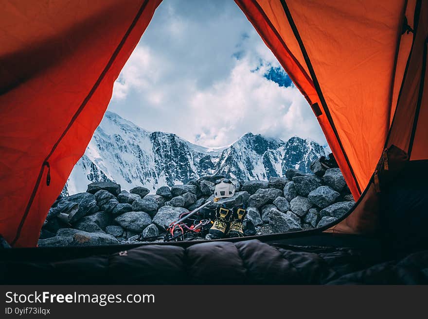 A morning view through the tent door, blue skies and a blanket of clouds at peaks, climbing gear after hike. A morning view through the tent door, blue skies and a blanket of clouds at peaks, climbing gear after hike