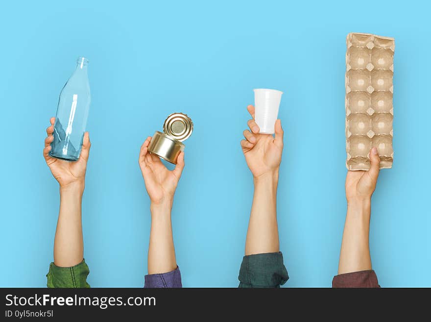 Different types of waste in the hands on a blue background. Sort garbage concept