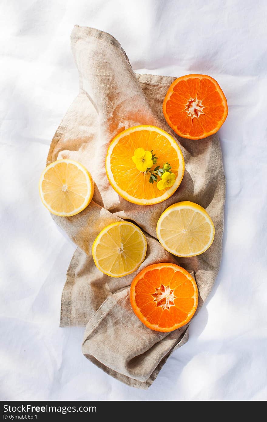 Juicy citrus fruits whole and cut on the tablecloth in the sun. Lemons and oranges. Healthy diet. Vitamins. Copy space