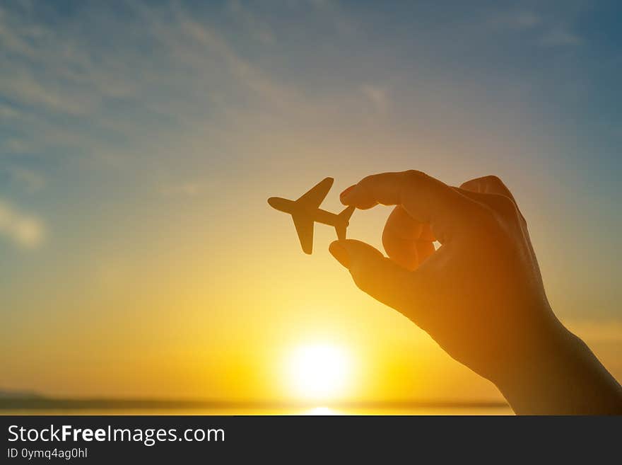 Airplane In Man Hand On Sunset Sky Background. Concept Airline