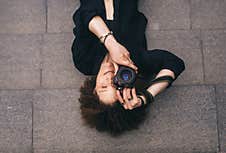 Brunette Woman With Digital 50mm Lens Reflex Camera Is Lying On The Steps. Top View Royalty Free Stock Image