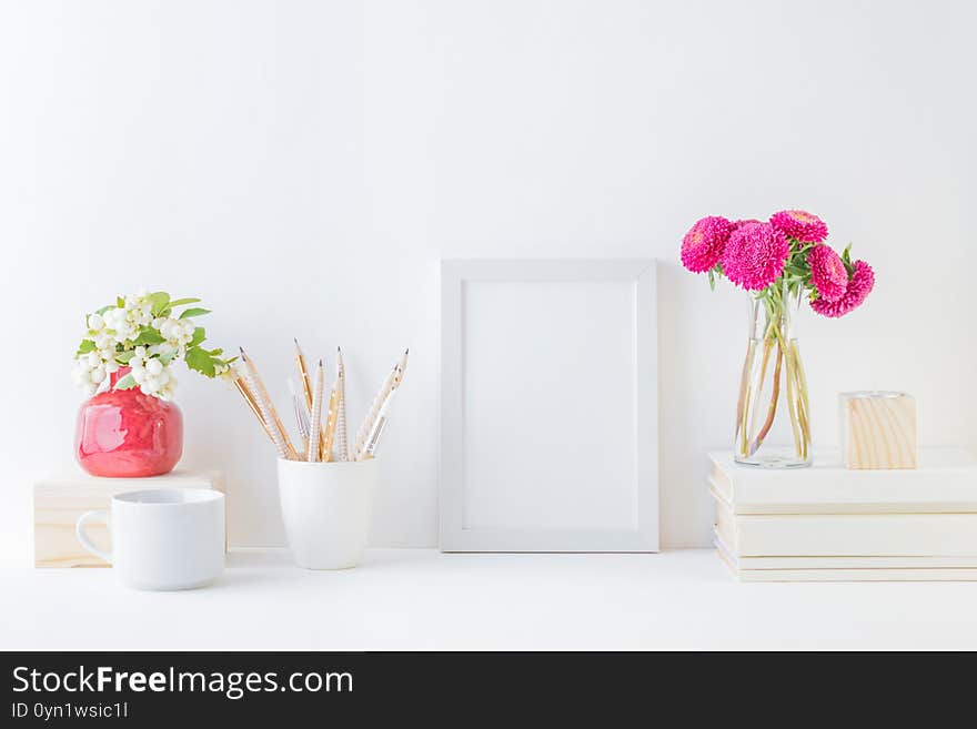 Home interior with decor elements. White frame, pink flowers in a vase, interior decoration