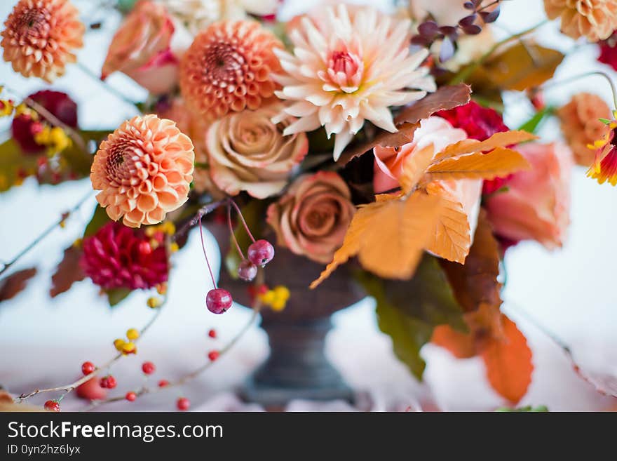 Beautiful flower composition with autumn orange and red flowers and berries. Autumn bouquet in vintage vase on a wooden table with pink tissue. Beautiful flower composition with autumn orange and red flowers and berries. Autumn bouquet in vintage vase on a wooden table with pink tissue