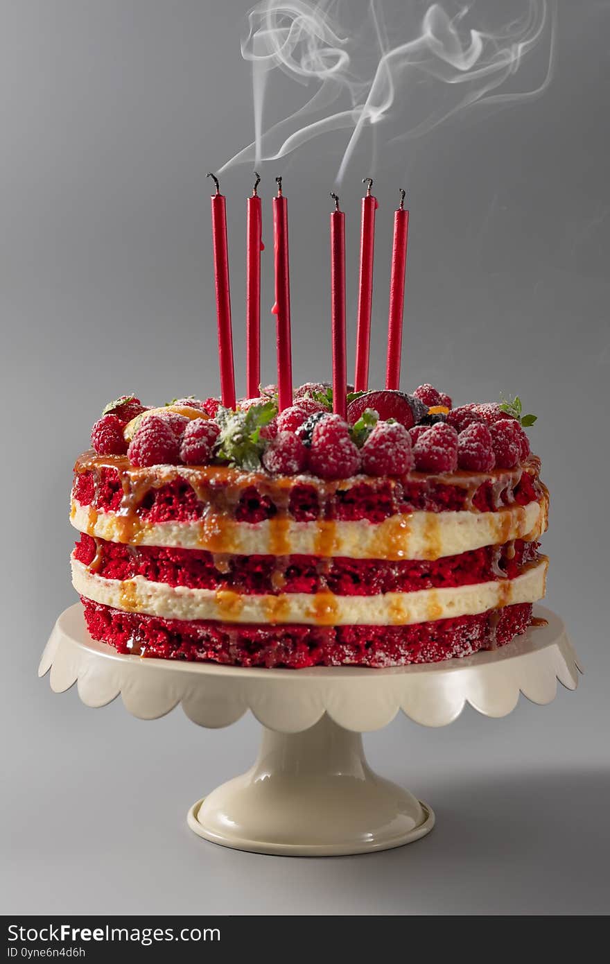 Birthday cake on a stand with blown out candles and smoke