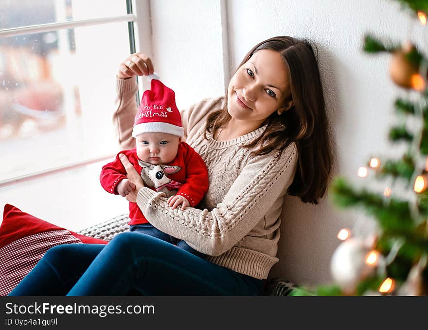 Mom and little child in santa costume on the background of a christmas tree. Mom and little child in santa costume on the background of a christmas tree