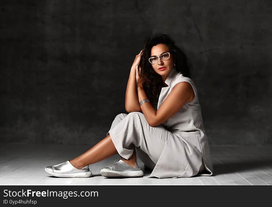 Charming Woman In Stylish Glasses, Trendy Wide Leg Capri Cropped Pants, Sleeveless Jacket And Silver Shoes Sits On The Floor