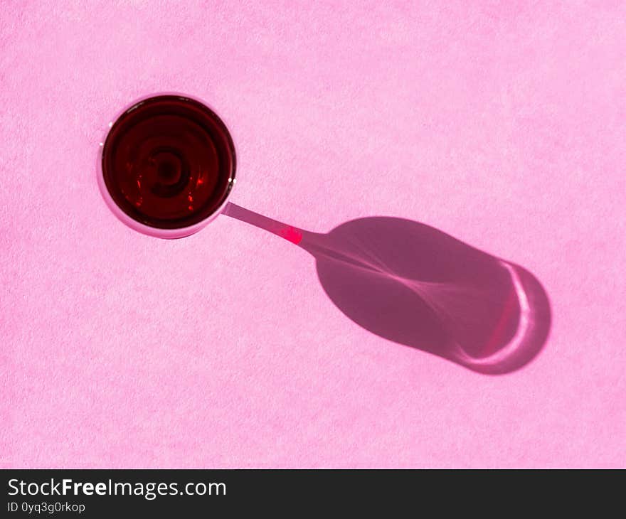 Wine Glass On A Pink Background With A Long Shadow. Creative Composition Of A Glass With A Shadow