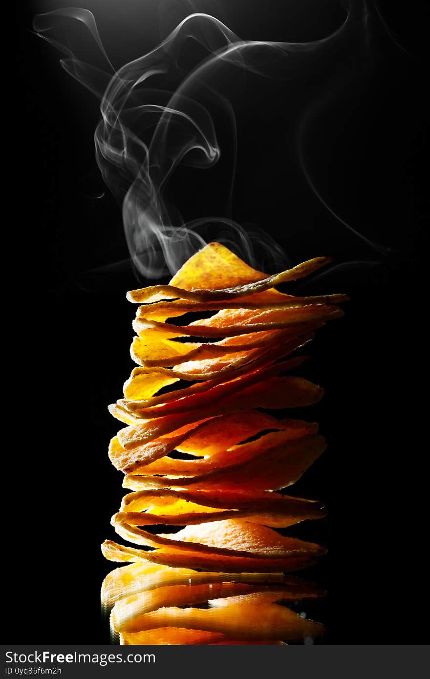 Hot mexican nachos tortilla chips stack with smoke, black background