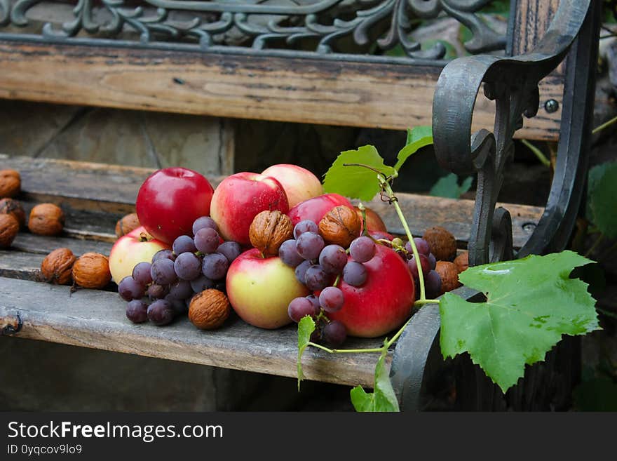 a basket with fruits and nuts on a forged bench. Apples, nuts, grapes