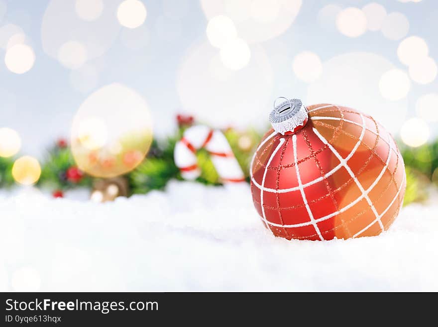 Christmas ball and fir branches with decorations on snow.