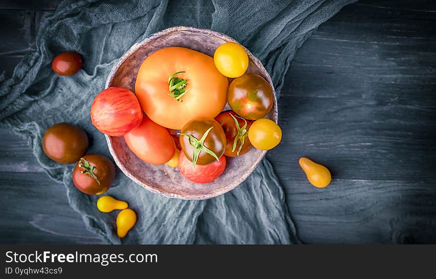 Organic yellow, red and orange tomatoes on a gray rustic wooden table. Copy space, panorama, top view