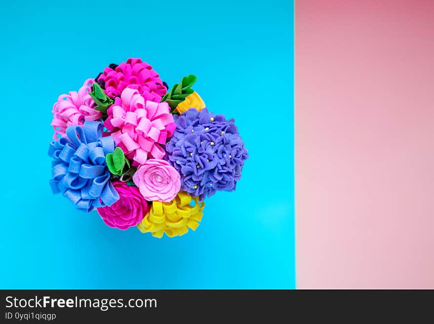 Bright handmade felt flowers on blue and pink background