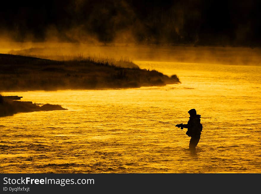 Silhouette of Fishing Flyfishing rod reel in river with golden sunlight. Silhouette of Fishing Flyfishing rod reel in river with golden sunlight