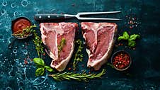 Dry Raw Two T-bone Steak On The Bone With Spices On A Black Stone Background. Top View. Rustic Style Royalty Free Stock Photography