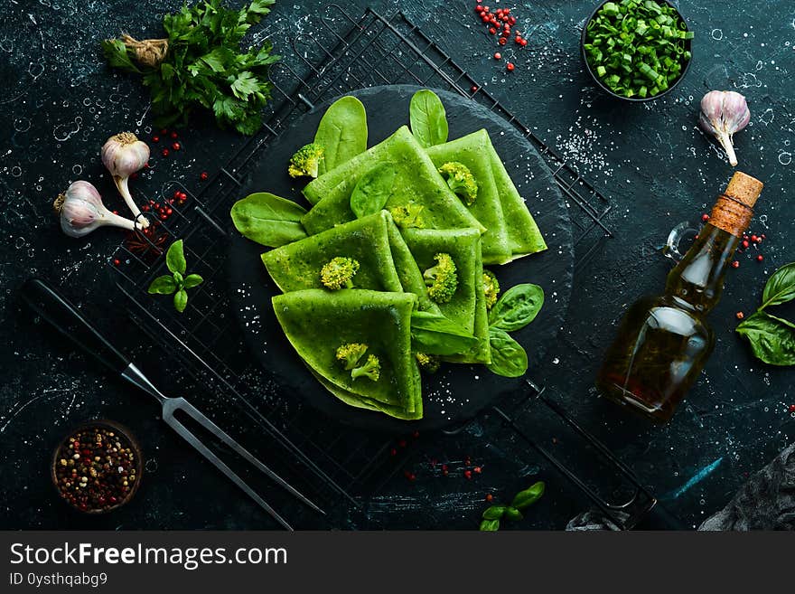 Vegetarian Food. Green Spinach pancakes with vegetables on a black stone plate. Top view. Free space for your text