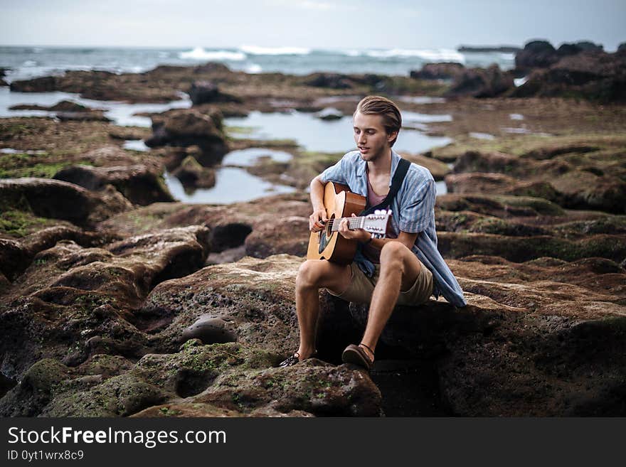 Romantic young man playing a guitar on the beach. Romantic young man playing a guitar on the beach