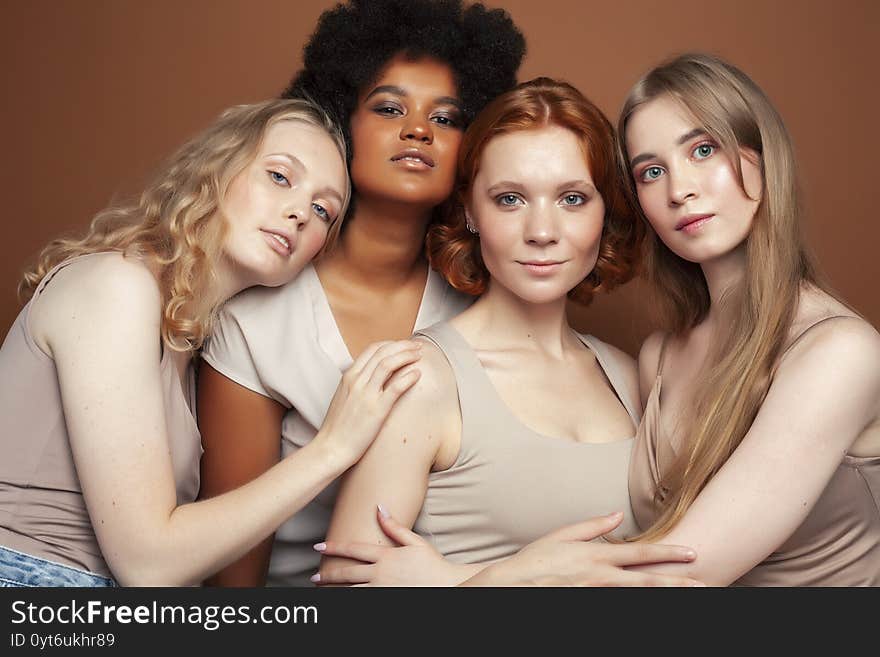 Young pretty african and caucasian women posing cheerful together on brown background, lifestyle diverse nationality people concept close up