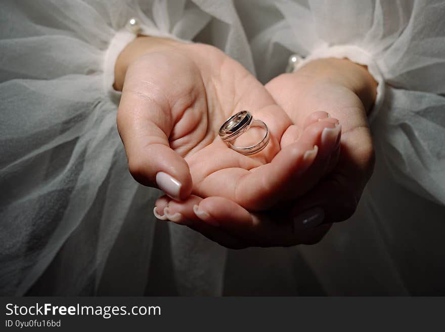 Two wedding rings in the hands of the newlyweds close up