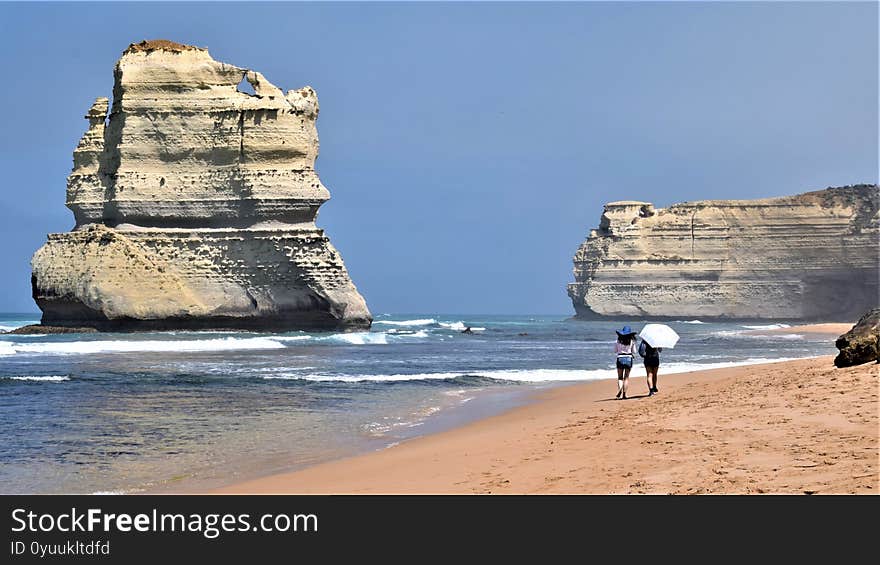 Two women walking beside rock formation