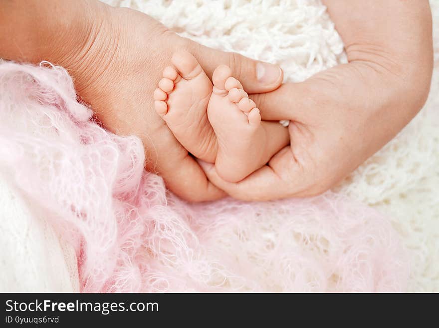 Baby feet in mother hands. Tiny Newborn Baby`s feet on female Shaped hands closeup. Mom and her Child. Happy Family concept. Beautiful conceptual image of Maternity