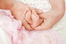 Baby Feet In Mother Hands. Tiny Newborn Baby`s Feet On Female Shaped Hands Closeup. Mom And Her Child. Happy Family Concept. Stock Photography