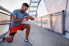 Young Handsome Sporty Jogger Taking Break From Exercising Outdoors Looking On A Smart Fitness Watch Royalty Free Stock Photography